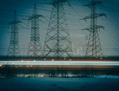 Electrónica y Electricidad para niños Moody night photo of electric towers silhouetted against an urban cityscape, highlighting powerful infrastructure.